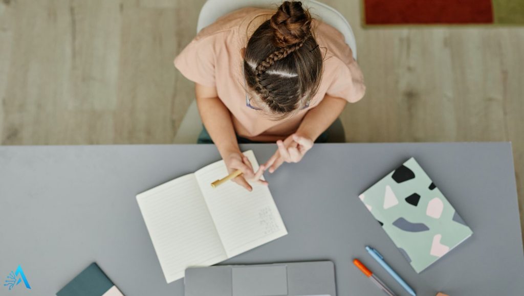 Young neurodivergent student using AI tools and a planner at a desk, representing focus and accessibility in learning
