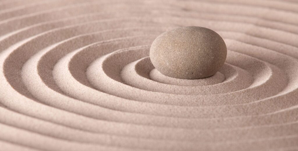 Zen stone in sand circles representing calm from AI meditation apps